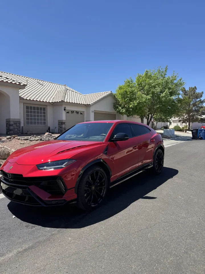 Red Lamborghini Urus with a clean, glossy finish in a residential street