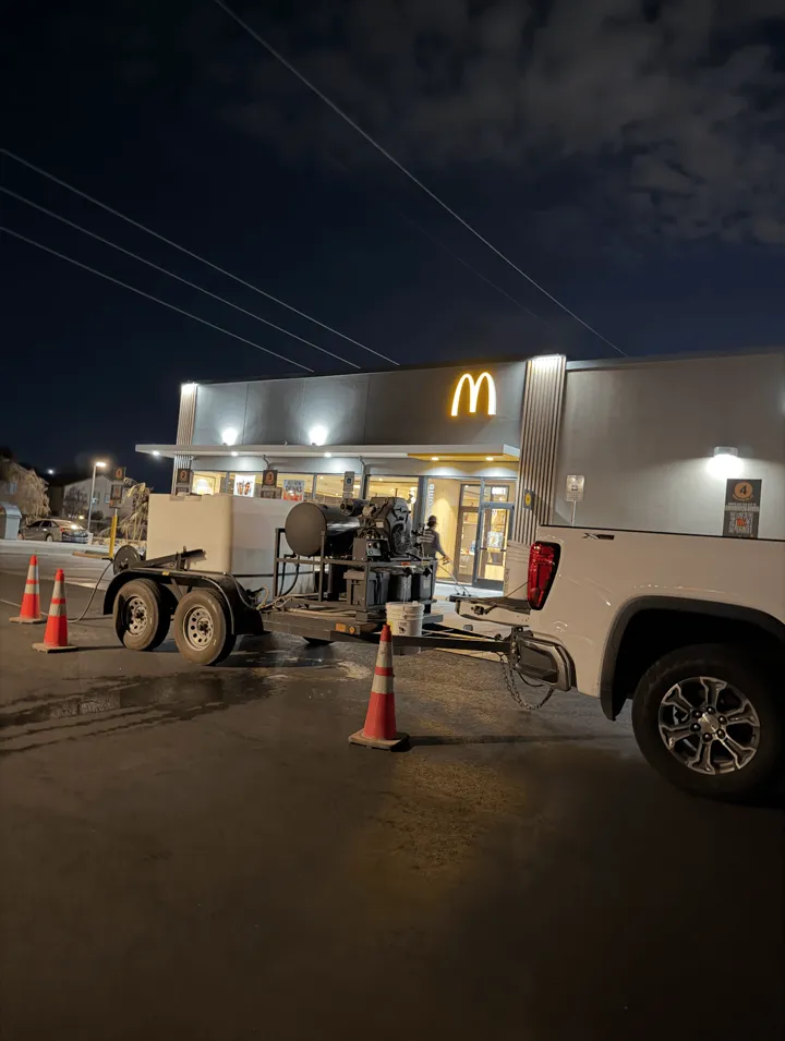 Night power washing setup with trailer and cones at a restaurant